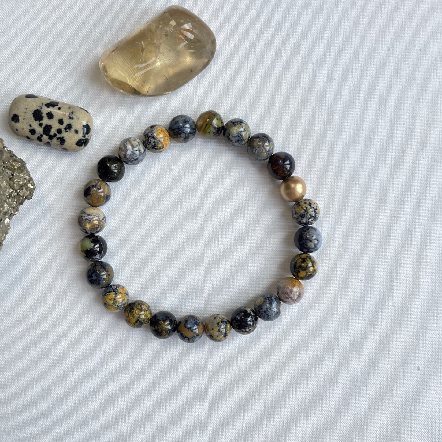 Deze stoere armband is geregen van oceaan jaspis kralen en een 14K gold filled kraal. De kralen hebben een gevarieerd vlekkenpatroon dat gaat van beige naar zwart. De kralen zijn 8 mm in doorsnede. De matte gold filled kraal is net iets kleiner.