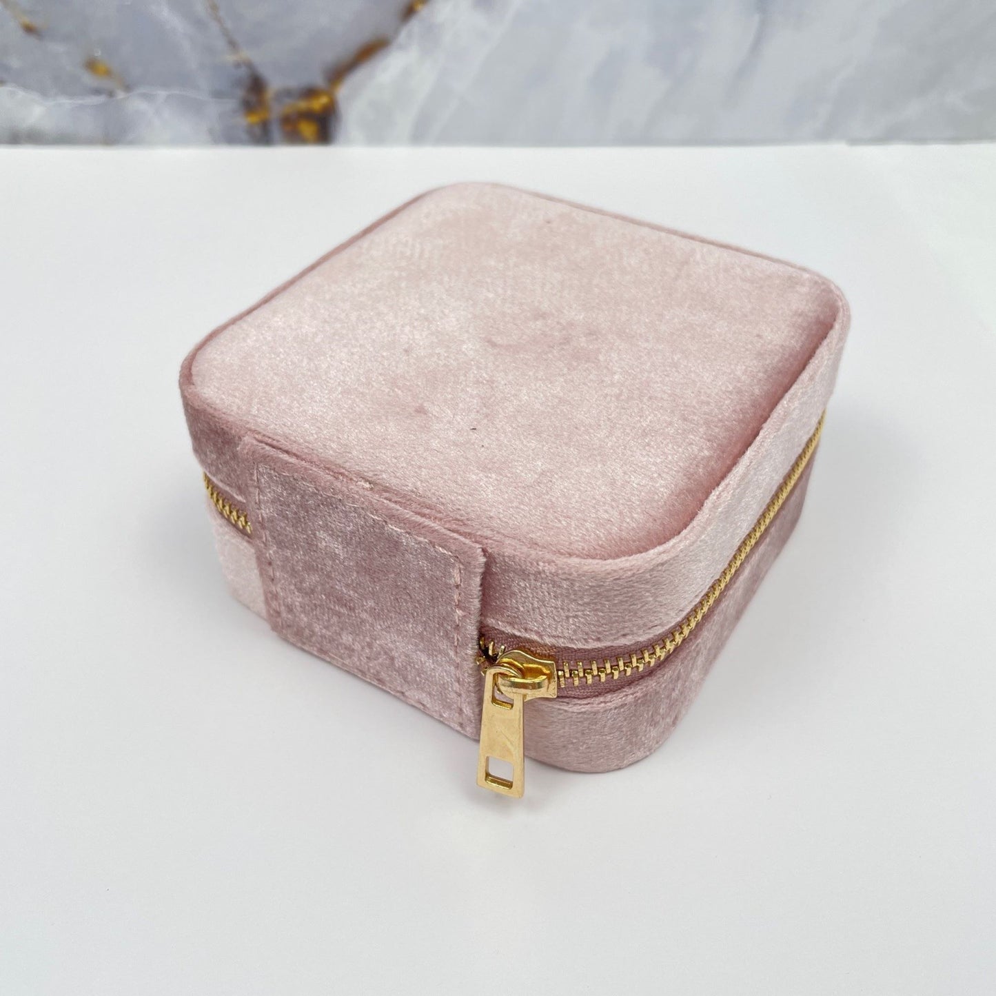 Vierkant klein sieraden doosje van zachtroze fluweel. Hier zie je de achterkant van het doosje met de grote goudkleurige rits.