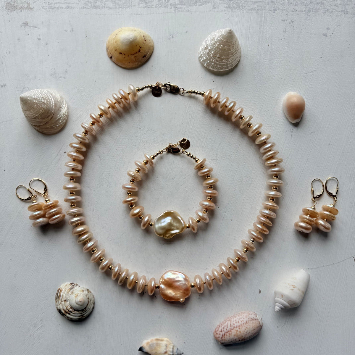 Set van armband, ketting en oorbellen van goudkleurige paresl omringd door verschillende schelpen - Engelina ewelry