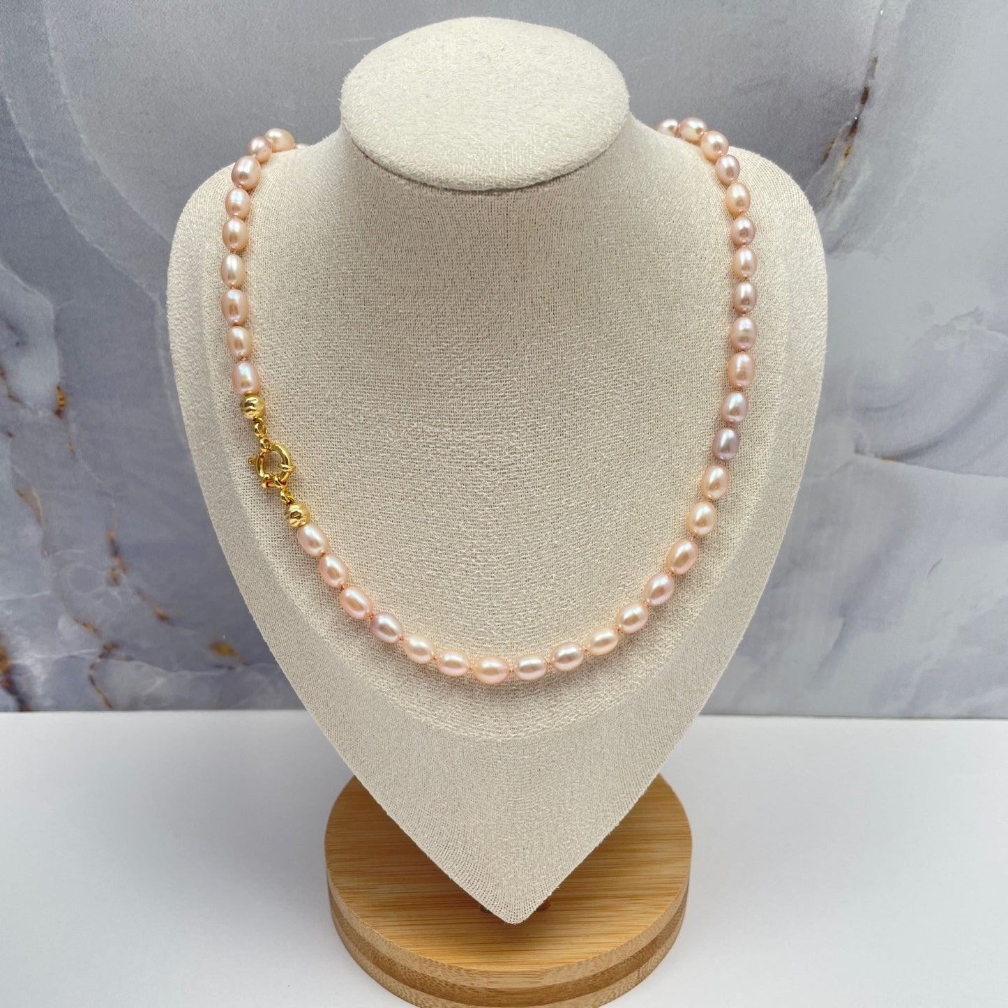 Ketting geknoopt met lichtroze zijden draad van natuurlijk roze zoetwaterparels. De parels hebben een mooie glans en de kleuren gaan van zachtroze, naar bijna lila. Ook zijn er twee bewerkte 14K gold filled kraken toegevoegd. De ketting sluit met een 14 gold filled boeislot. Hier hangt de ketting op een display.