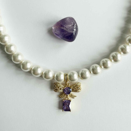 Ketting van schelpparels met paars strikje