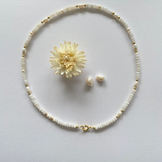 Ketting van witte jade afgewisseld met zoetwaterparels en gold filled kraaltjes. De ketting sluit met een veerslot. In het miden van de ketting ligt een witte droogbloem en twee parels.