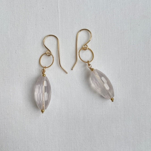 Aan een 14K gold filled haakje met ook nog een bewerkte 14K goldfilled ring, hangt een transparante rozenkwarts druppel. De druppel is facet geslepen, zodat deze mooi het licht vangt.