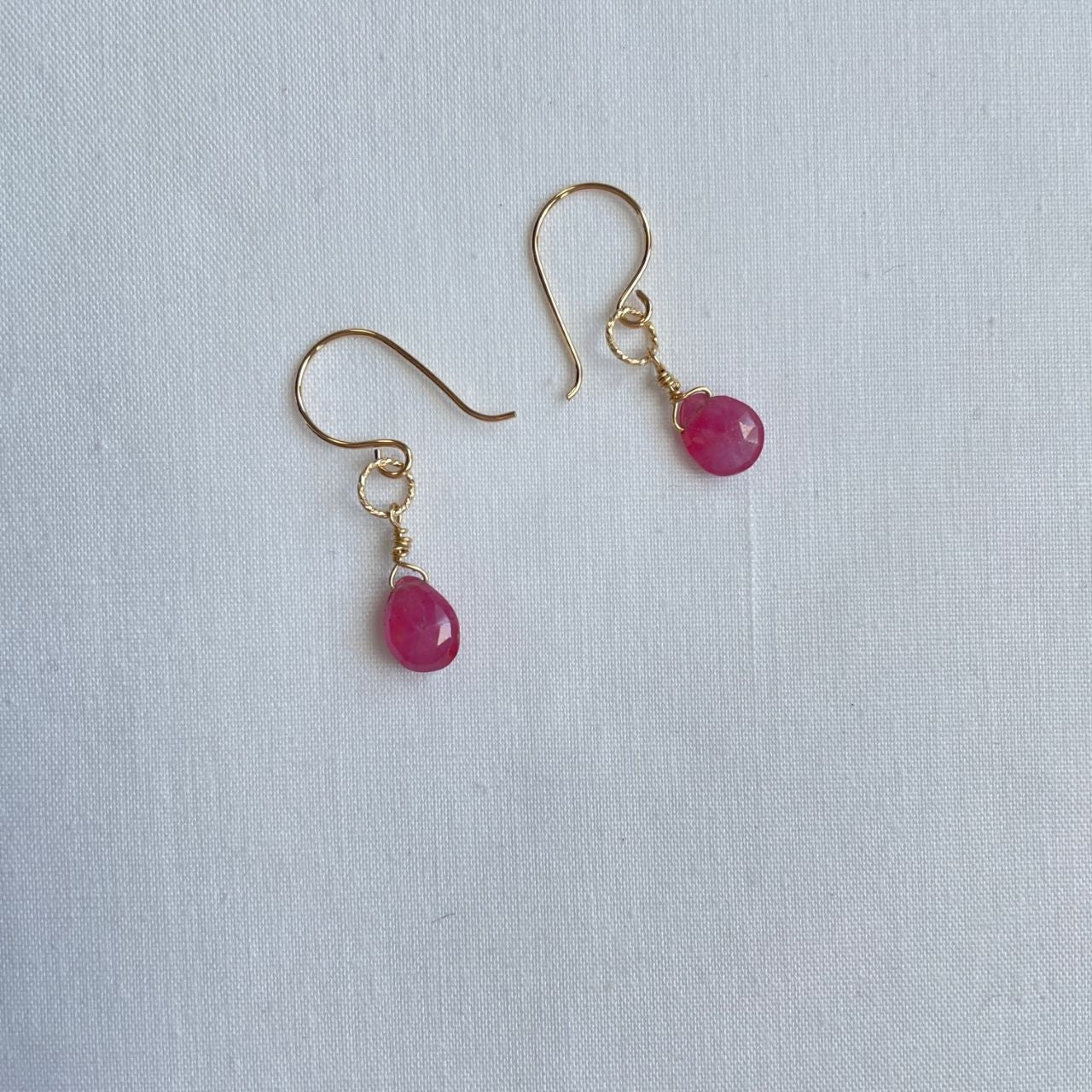 Aan een 14K gold filled haakje hangt aan een bewerkt ringetje een kleine roze saffier druppel. De druppel is facet geslepen, zodat de oorbellen nog meer licht vangen.