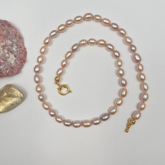 Ketting geknoopt met lichtroze zijden draad van natuurlijk roze zoetwaterparels. De parels hebben een mooie glans en de kleuren gaan van zachtroze, naar bijna lila. Ook zijn er twee bewerkte 14K gold filled kraken toegevoegd. De ketting sluit met een 14 gold filled boeislot.
