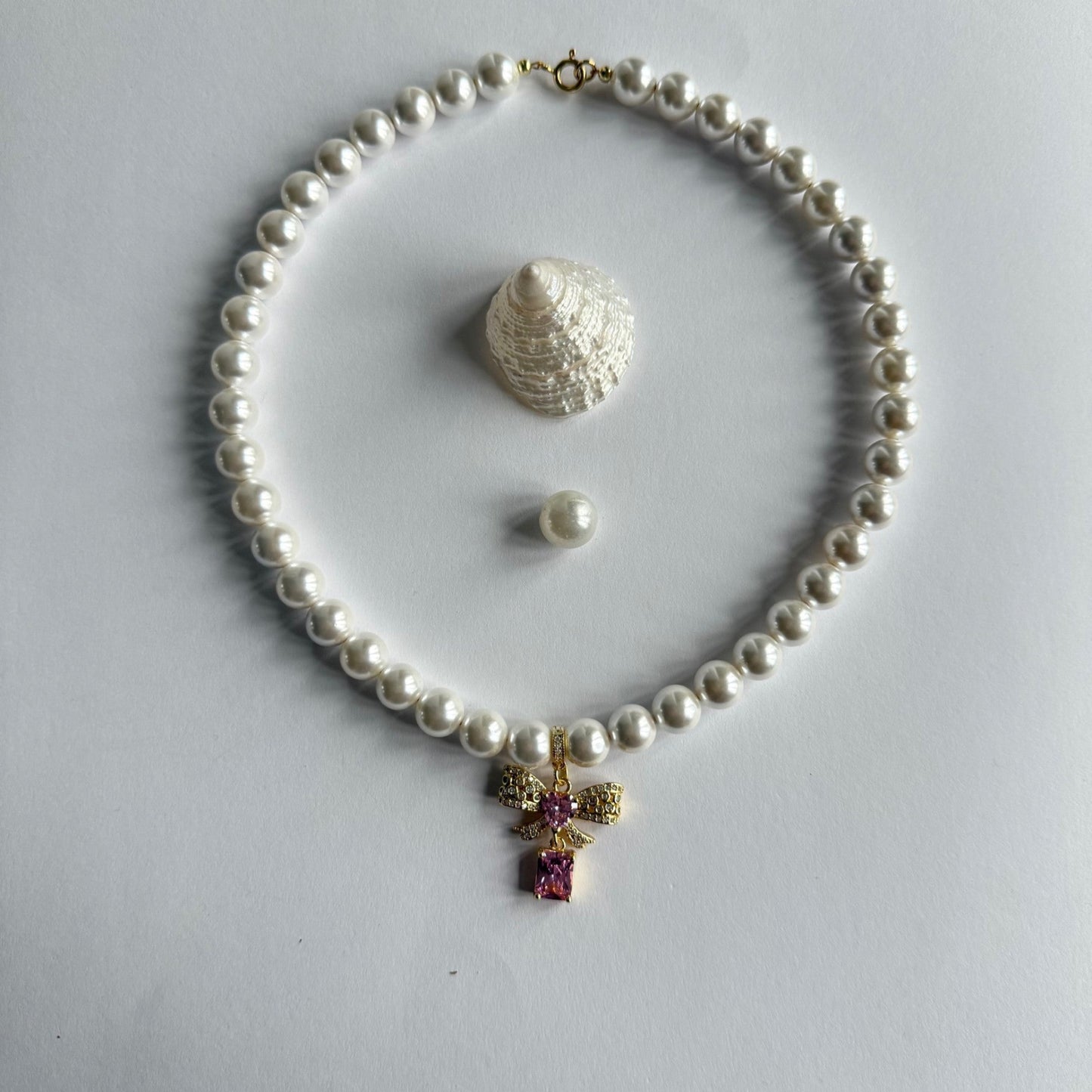 Ketting van schelpparels met roze strikje