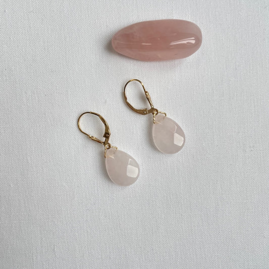 Deze 14K gold filled oorbelletjes met brisure sluiting hebben aan de voorkant een leliebloem. Aan een bewerkt driehoekje hangt een mooie rozenkwarts druppel. De druppel is facet geslepen voor extra schittering. De druppels zijn licht van kleur en hier en daar transparant.